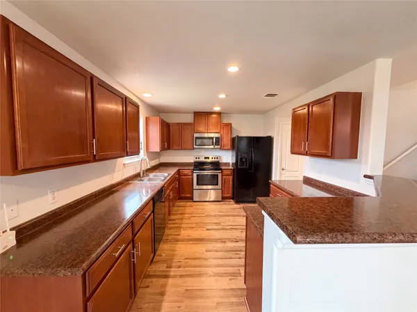 a large kitchen with stainless steel appliances wooden cabinets a stove and a center island