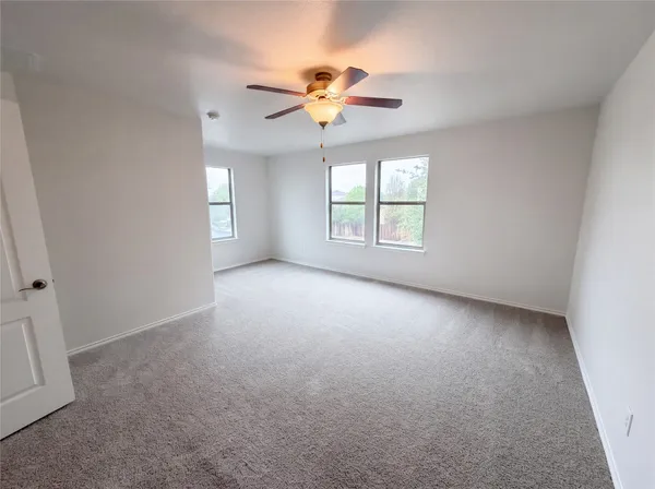 an empty room with windows and chandelier fan