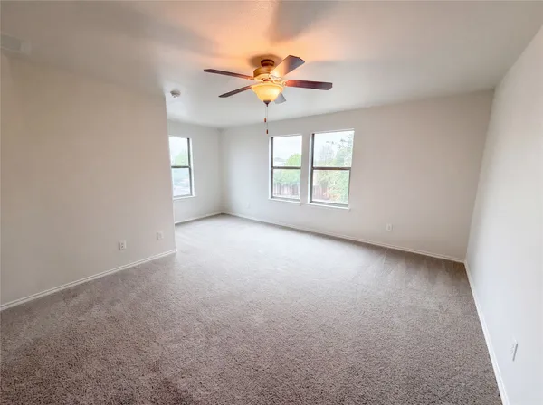 an empty room with windows and chandelier fan