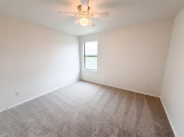 an empty room with a window and a fan