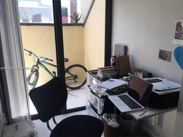 a view of a workspace with furniture and a window