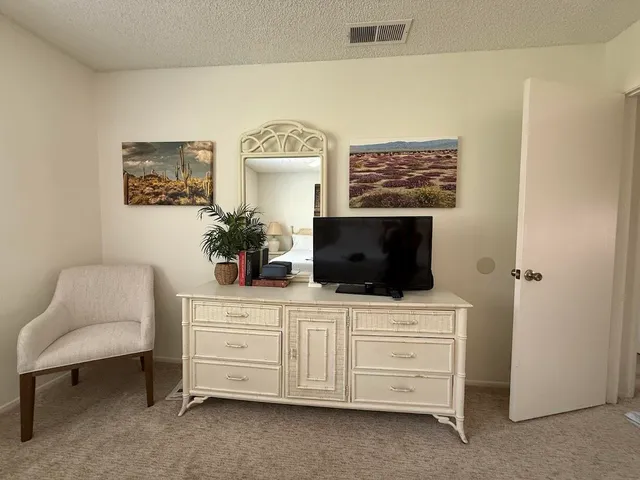 a bedroom with a large bed a flat tv screen and chandelier