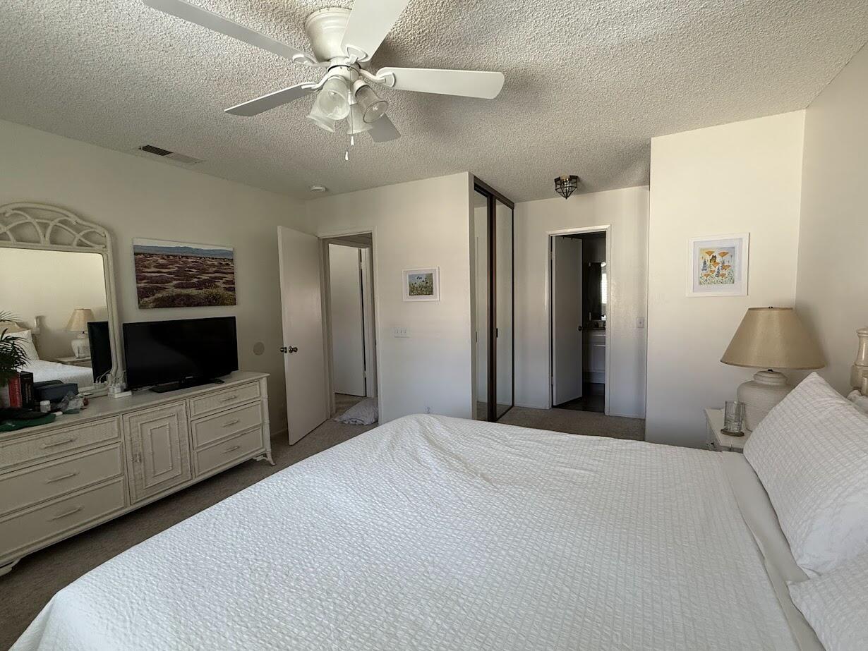 72822 Tony Trabert Lane Palm Desert, CA 92260 - Photo 17 of 23 a bedroom with a large bed a flat tv screen and chandelier