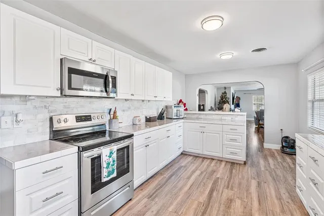 a kitchen with granite countertop cabinets stainless steel appliances and wooden floor
