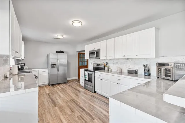 a large kitchen with cabinets wooden floor and stainless steel appliances