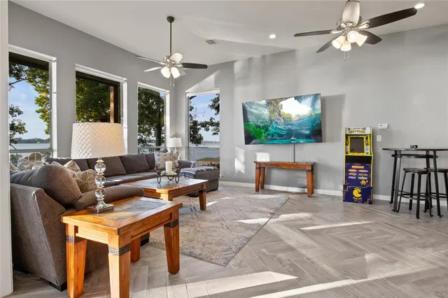 a living room with furniture a flat screen tv and floor to ceiling windows