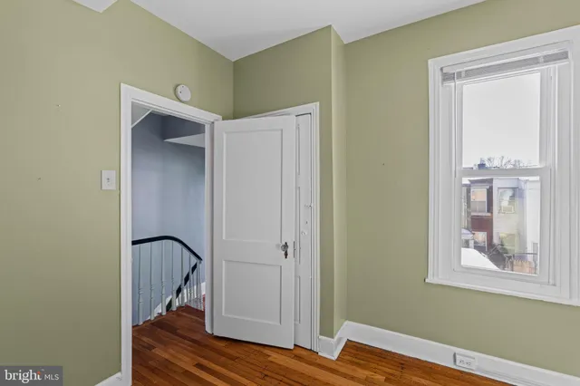 a view of an empty room with window and wooden floor