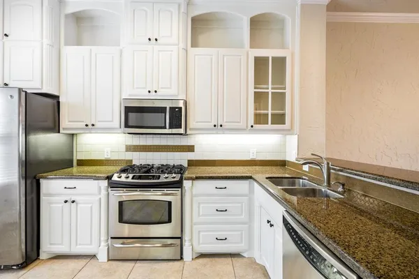 a kitchen with granite countertop a stove sink and microwave