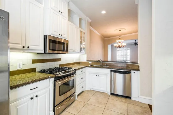 a kitchen with stainless steel appliances granite countertop a stove a sink and a microwave