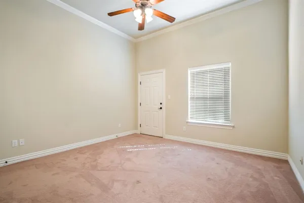 an empty room with a chandelier fan and windows