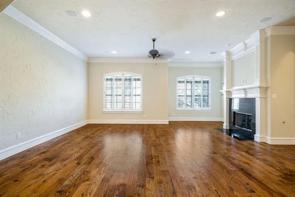 an empty room with wooden floor fireplace and windows