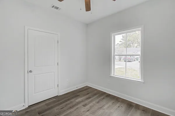 an empty room with wooden floor cabinet and windows
