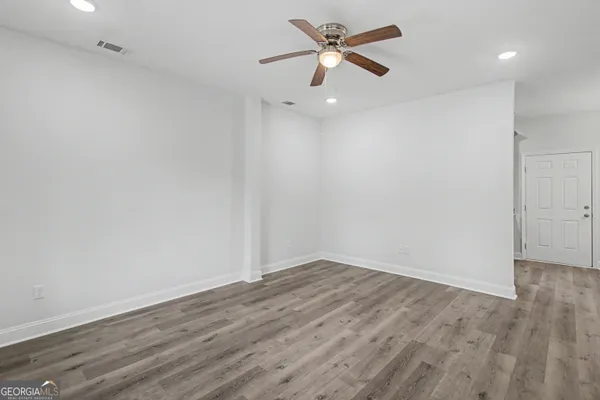 an empty room with wooden floor and a ceiling fan