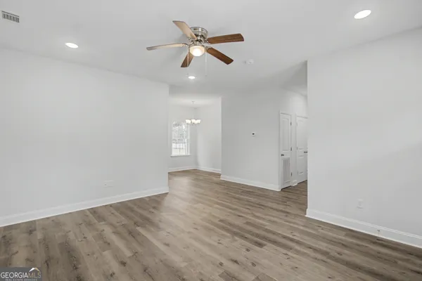an empty room with wooden floor ceiling fan and windows