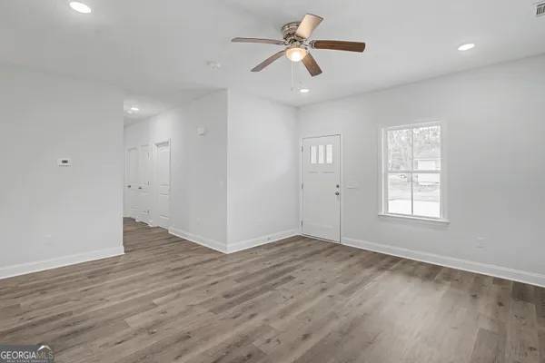 a view of an empty room with wooden floor and a window