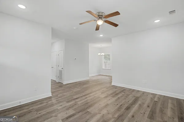an empty room with wooden floor and a ceiling fan