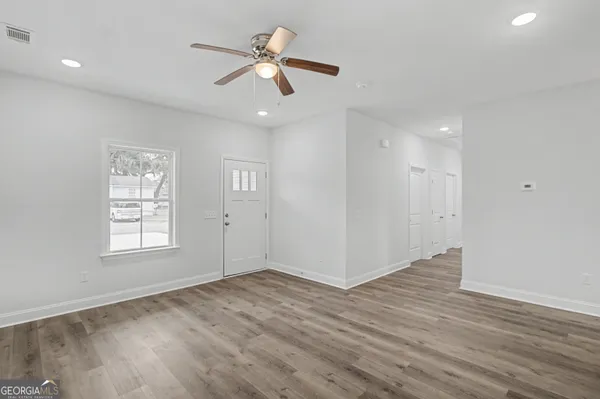 a view of an empty room with wooden floor and a window