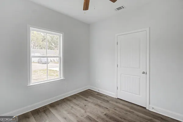an empty room with wooden floor cabinet and windows