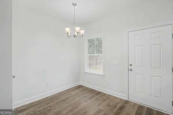 a view of empty room with wooden floor and chandelier