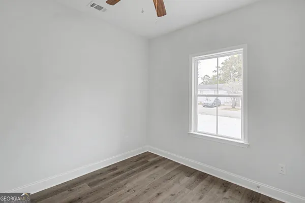 an empty room with wooden floor and windows