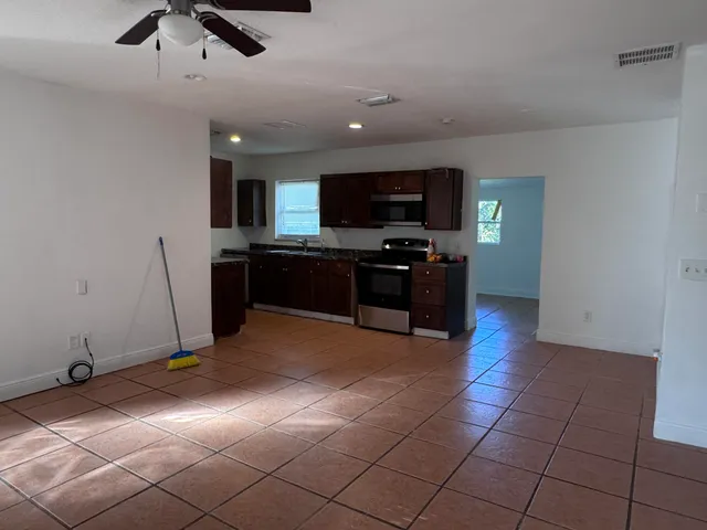 a living room with stainless steel appliances furniture and a flat screen tv