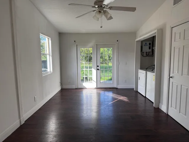 a view of an empty room with wooden floor and a window