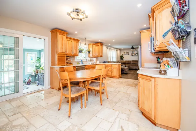 a open kitchen with stainless steel appliances kitchen island granite countertop a refrigerator a stove top oven and a view of living room