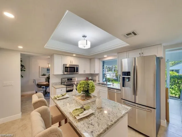 a living room with stainless steel appliances furniture a rug and a kitchen view