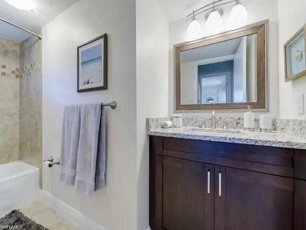 a bathroom with a granite countertop sink mirror and a bathtub