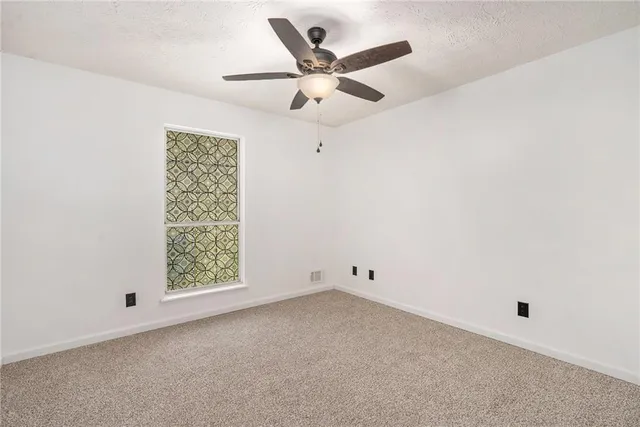 an empty room with ceiling fan and window