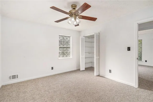 an empty room with windows and ceiling fan