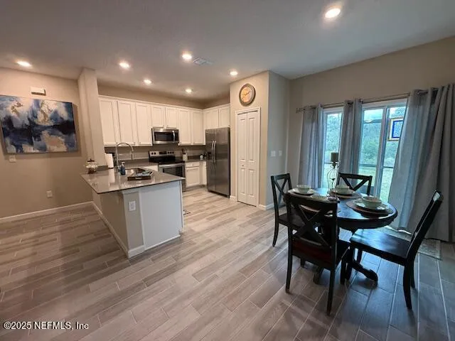 a kitchen with stainless steel appliances kitchen island granite countertop a table chairs and a stove