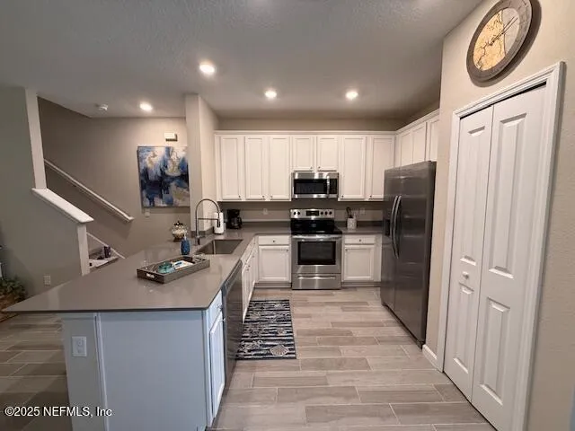 a kitchen with kitchen island granite countertop appliances cabinets a sink and a refrigerator