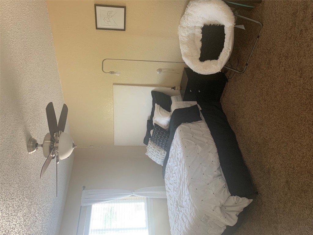 2401 Manor Road, Unit 218 Austin, TX 78722 - Photo 5 of 8 a bedroom with a bed and a chandelier