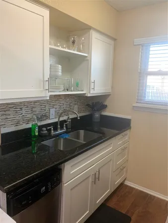 a kitchen with granite countertop a sink and a white wooden cabinets