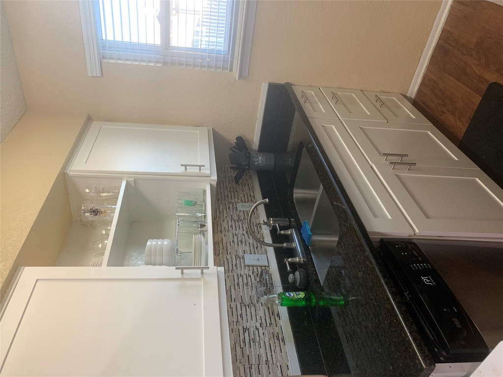 2401 Manor Road, Unit 218 Austin, TX 78722 - Photo 6 of 8 a kitchen with granite countertop a sink and a white wooden cabinets