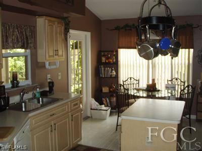 9167 Henry Road Fort Myers, FL 33967 - Photo 3 of 10 a kitchen with a stove a refrigerator and a dining table with wooden cabinet