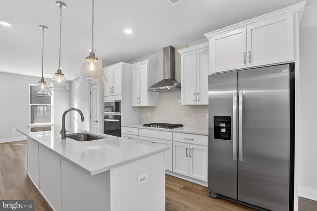 a kitchen with stainless steel appliances granite countertop a sink a refrigerator and a stove