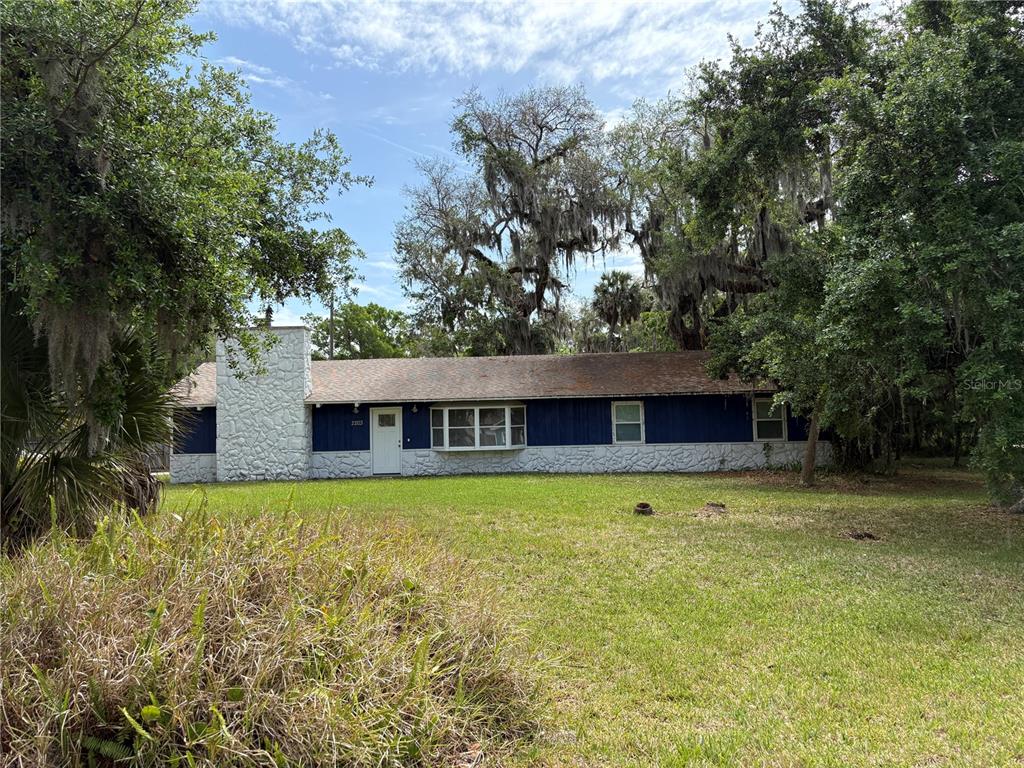 a front view of house with yard and trees in the background