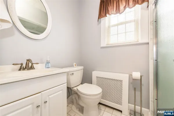 a bathroom with a toilet a sink a mirror and a window