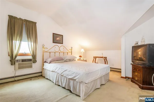 a bedroom with a bed flat screen tv and a window