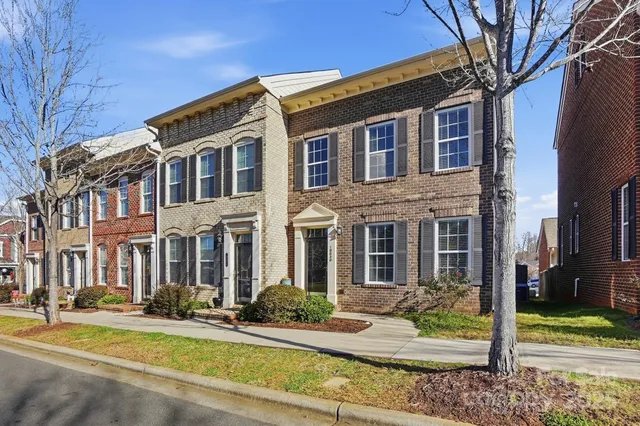 a view of a brick house with many windows next to a road