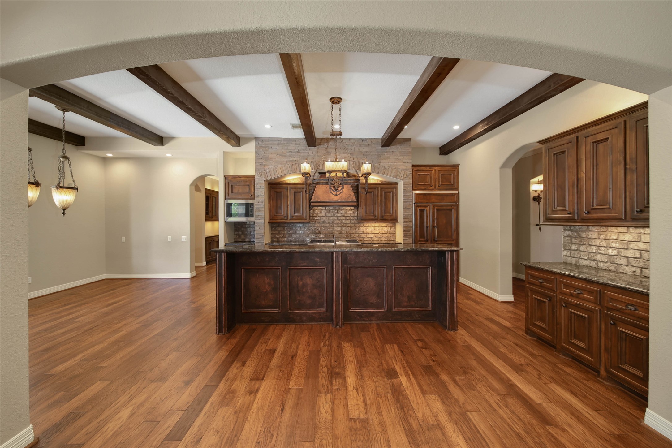 6803 Star Ledge Court Spring, TX 77389 - Photo 11 of 48 Stunning island kitchen with beamed ceiling, recessed lighting, custom cabinetry, and rich wood opens to the Family Room and Breakfast Room