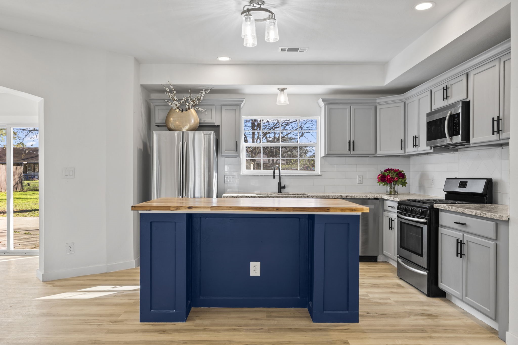 1740 6th Street Hempstead, TX 77445 - Photo 14 of 22 Stunning kitchen featuring gray cabinetry, stainless steel appliances, and a bold navy island with butcher-block top—ideal for gathering and meal prep.