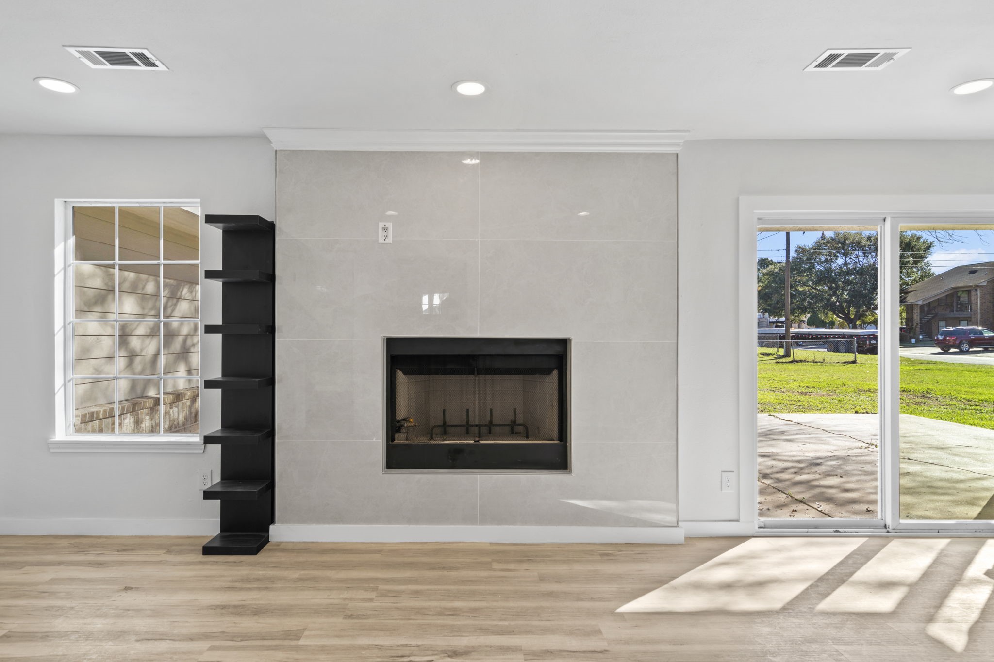 1740 6th Street Hempstead, TX 77445 - Photo 17 of 22 Modern tiled fireplace with clean lines and custom built-in shelving anchors the living area and creates a warm focal point.