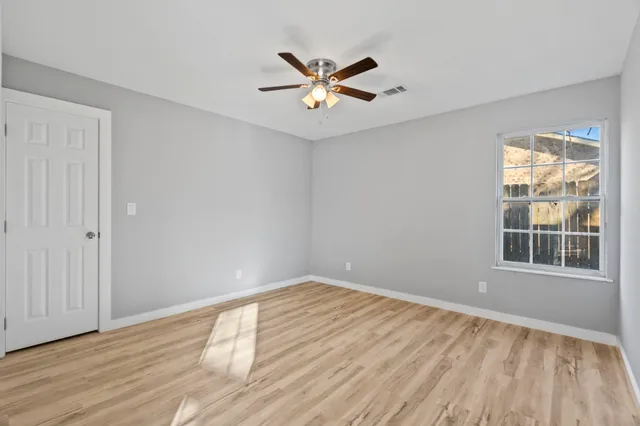 a view of empty room with wooden floor and fan