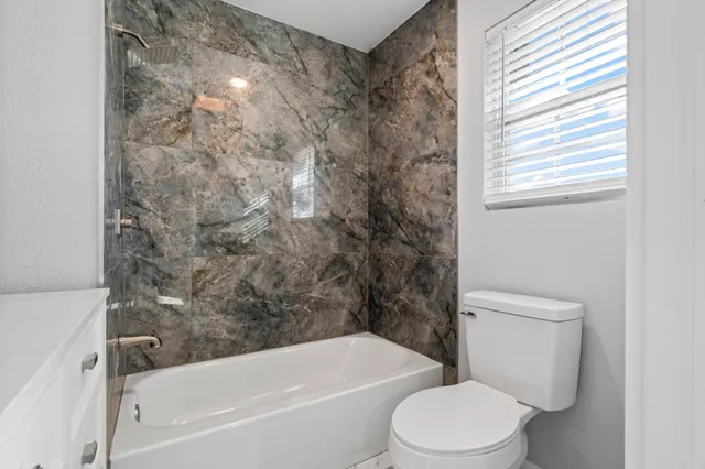 a white toilet sitting next to a bath tub