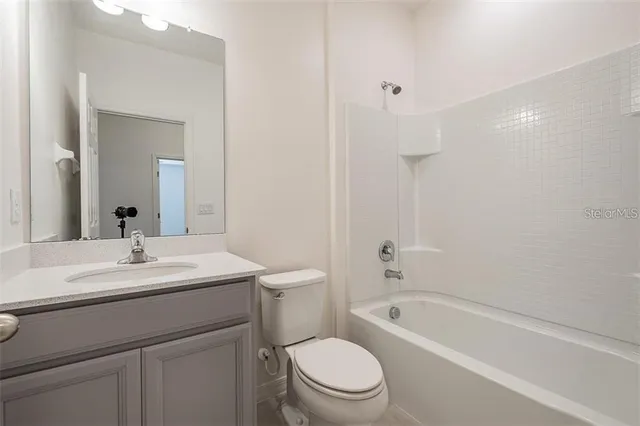 a bathroom with a toilet a sink a mirror a bathtub and vanity