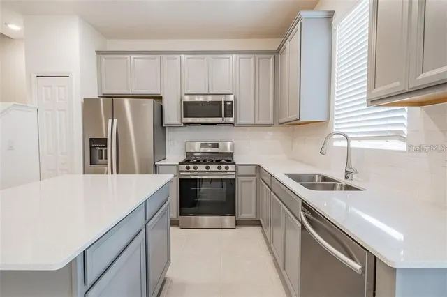 a kitchen with stainless steel appliances a sink stove refrigerator and a window