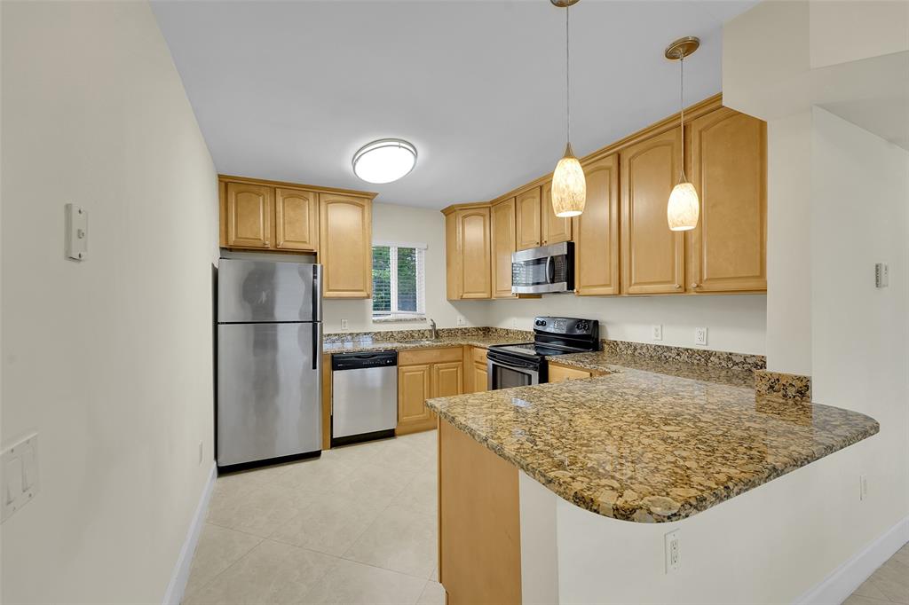 410 Southwest 15th Street, Unit 103 Pompano Beach, FL 33060 - Photo 6 of 16 a kitchen with refrigerator and cabinets